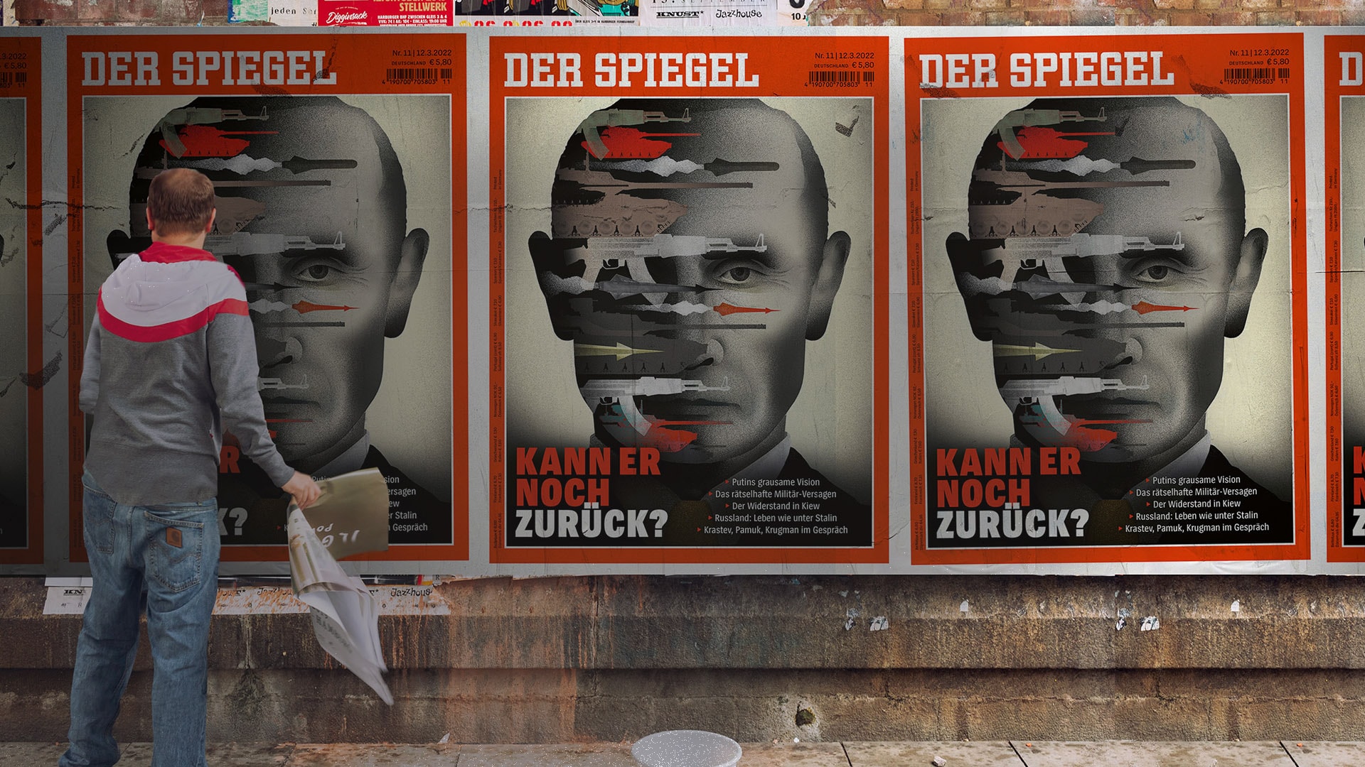 Person viewing Der Spiegel magazine posters on wall