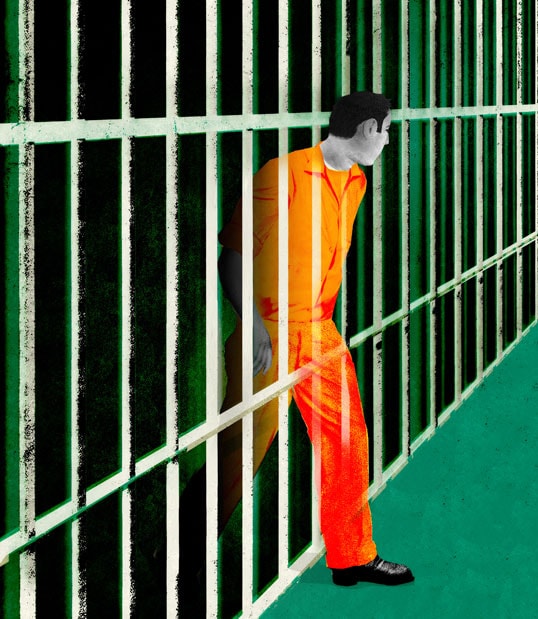Prisoner in orange jumpsuit behind bars